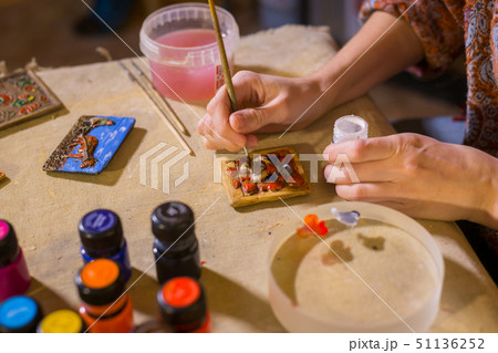 Professional woman potter painting ceramic souvenir magnet in potter 51136252