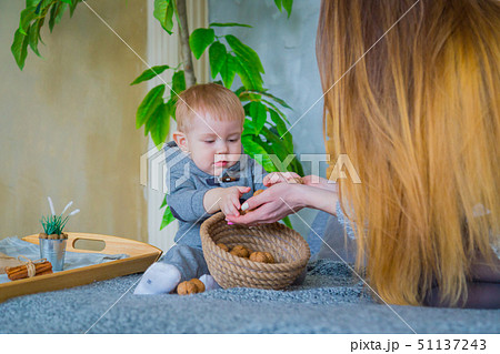 Happy young mother and her baby son playing with walnuts Happy young mother and her baby son playing with walnuts 51137243
