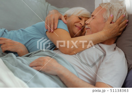Loving wife tenderly hugging her spouse while lying with him 51138363