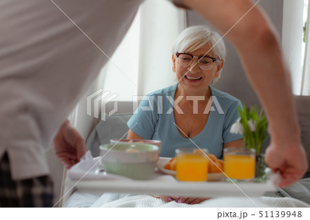 Contended lady looking at breakfast while lying in the bed Contended lady looking at breakfast while lying in the bed 51139948