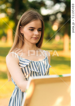Portrait of Blond hair girl in dress drawing a picture in the park Portrait of Blond hair girl in dress drawing a picture in the park 51195469