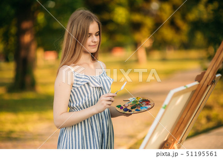 Portrait of Blond hair girl in dress drawing a picture in the park 51195561