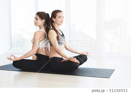 Two attractive women in sportswear on white background doing yoga Two attractive women in sportswear on white background doing yoga 51230351