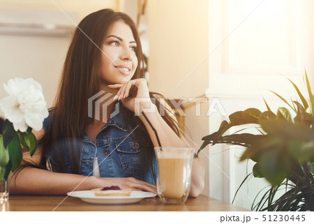 Young beautiful girl sitting in cafe and dreaming Young beautiful girl sitting in cafe and dreaming 51230445