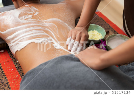 Asian woman enjoying a salt scrub massage at spa. Asian woman enjoying a salt scrub massage at spa. 51317134