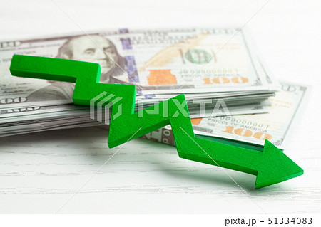 Red arrow down amid wads of cash and staff. The fall or bankruptcy of profits from the business. Red arrow down amid wads of cash and staff. The fall or bankruptcy of profits from the business. 51334083