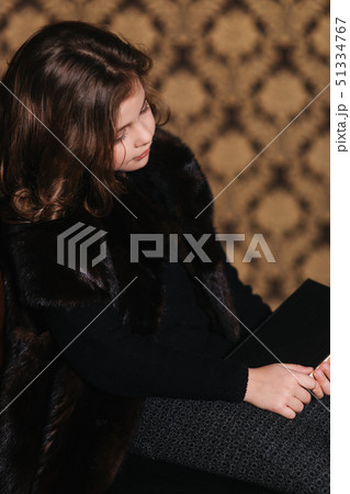 Beautiful little girl is reading a book in the library. Preparing for a school Beautiful little girl is reading a book in the library. Preparing for a school 51334767