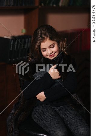 Beautiful little girl is reading a book in the library. Preparing for a school Beautiful little girl is reading a book in the library. Preparing for a school 51334776