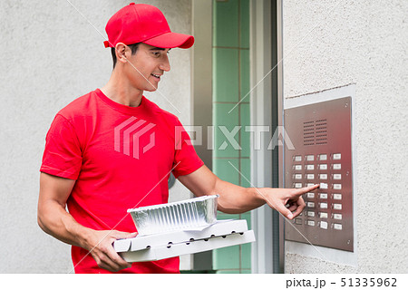 Pizza delivery man carrying boxes using the intercom 51335962