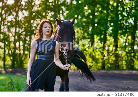 A young slim brunette woman in a black dress 51337486