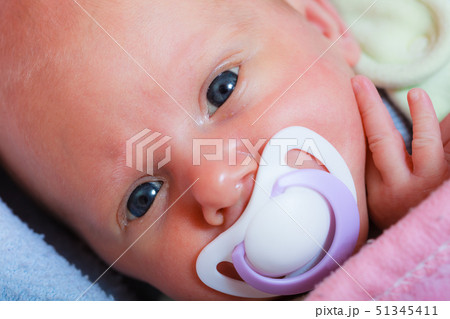 Newborn baby lying in bed with dummy Newborn baby lying in bed with dummy 51345411