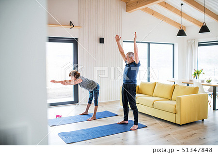 A senior couple indoors at home, doing exercise in living room. 51347848