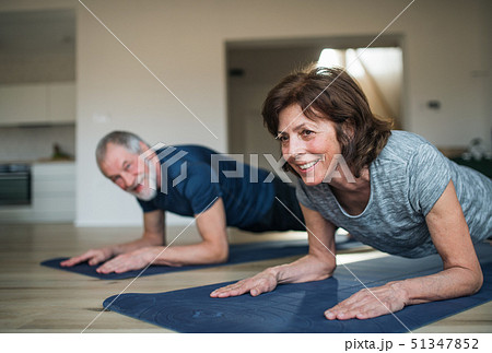 A senior couple indoors at home, doing exercise on the floor. A senior couple indoors at home, doing exercise on the floor. 51347852
