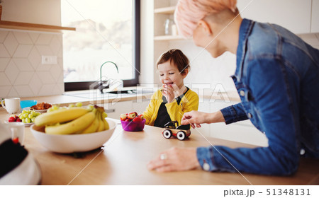 A young woman with a small daughter spending time together in a kitchen. A young woman with a small daughter spending time together in a kitchen. 51348131
