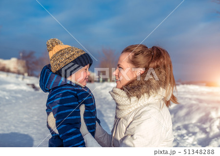 Woman mother with child winter city, warm clothes, little boy 3 years old in blue jumpsuit and hat 51348288