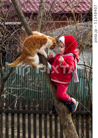 A little girl in red dressed up on a tree in the 51348407