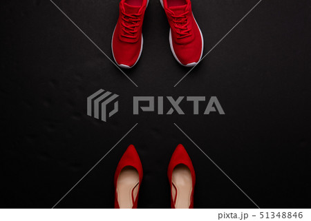 A studio shot of pair of running vs high heel shoes on black background. Flat lay. A studio shot of pair of running vs high heel shoes on black background. Flat lay. 51348846