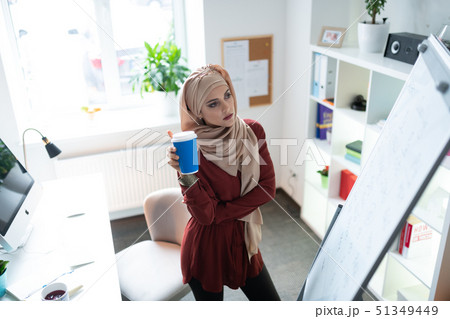 Teacher drinking takeaway coffee and looking at whiteboard Teacher drinking takeaway coffee and looking at whiteboard 51349449