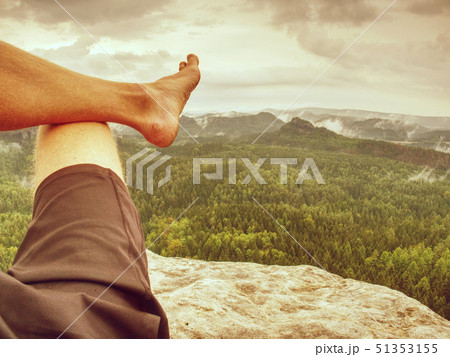 Young man sit down on mountain edge barefoot. Young man sit down on mountain edge barefoot. 51353155