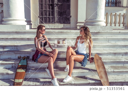 Two girls friends girlfriends, sitting on steps institute and college, talking talk, skate 51353561