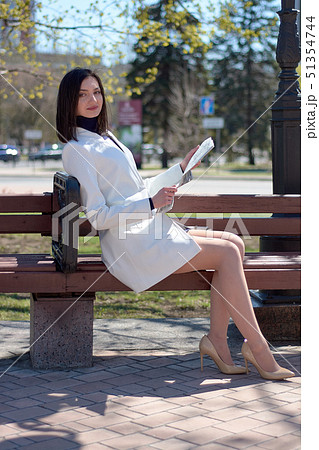 Elegant young woman on a city street with a newspaper in her hands. Elegant young woman on a city street with a newspaper in her hands. 51354744