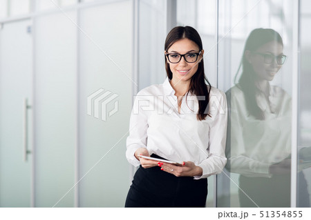 Young business woman with tablet computer opening glass office door Young business woman with tablet computer opening glass office door 51354855