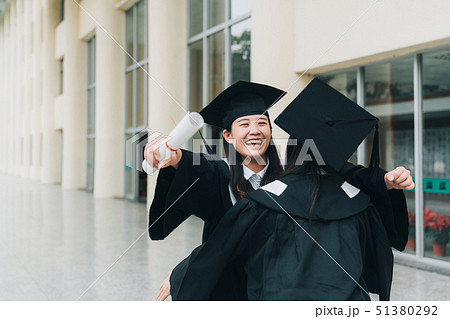graduates holding diploma walking close hugging 51380292