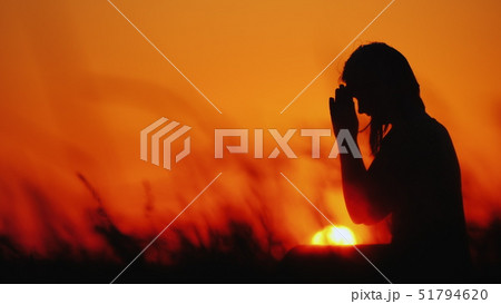 Profile of a woman in prayer at sunset 51794620