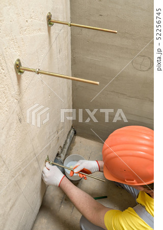 The worker is fixing up a wall of bolts. 52256745