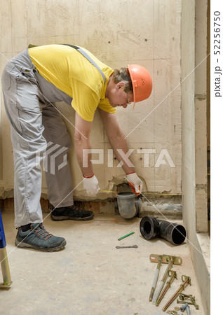 The worker is installing a sewage drain pipe. 52256750