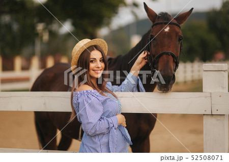 Pregnant woman walk though the farm and make a photo near the hors. Beautiful farm animal. Brown Pregnant woman walk though the farm and make a photo near the hors. Beautiful farm animal. Brown 52508071