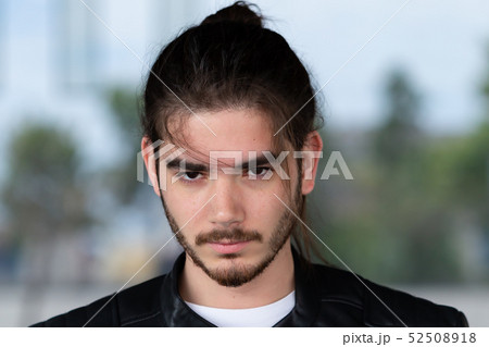 Handsome young bearded man posing outside. 52508918