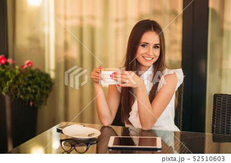 Young girl use a tablet and drink cappuccino. The girl in the cafe. Happy attractive woman on 52510603