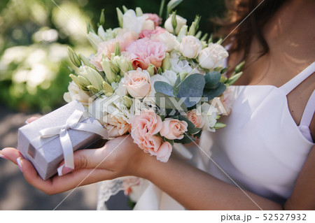 Girl hold a bouquet and ring box in hands. french manicure. Female is dressed in white dress 52527932