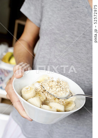 young man eating some porridge young man eating some porridge 52572975