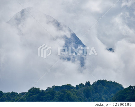 High mountain with green slopes hidden in clouds 52590199
