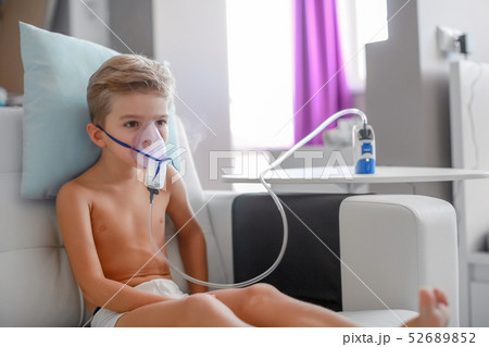 sick boy in nebulizer mask making inhalation, respiratory procedure by pneumonia or cough for child 52689852