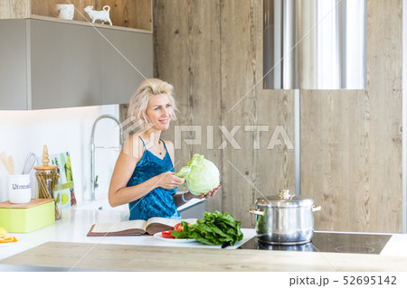 young blonde woman cooking in modern kitchen 52695142