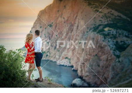 Happy young family pregnant pretty girl with husband on the cliff in mountains over sunset lights Happy young family pregnant pretty girl with husband on the cliff in mountains over sunset lights 52697271