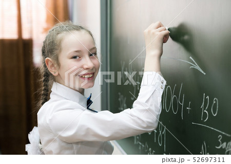 A girl female elementary school student writes on 52697311