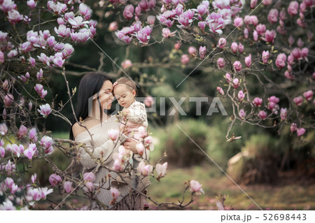 Young mother and little daughter in autumn park play with magnolia leaves. Happy weekend with family 52698443