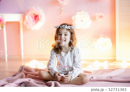 A little girl in a homely atmosphere against a wall with glowing lights. 52731365