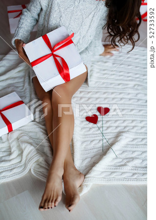 Girl with beautiful legs holds white box wrapped with red ribbon. Girl with beautiful legs holds white box wrapped with red ribbon. 52733592