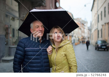 Close up portrait of elderly man and his young blonde-haired wife embracing each other and standing Close up portrait of elderly man and his young blonde-haired wife embracing each other and standing 52766248