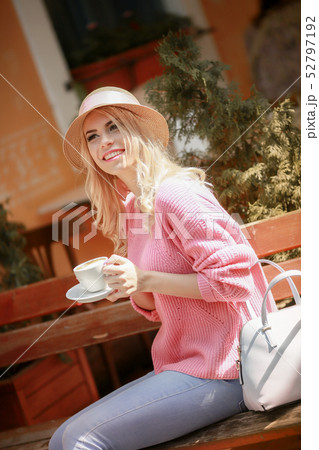 Beautiful girl in a pink dress sitting in a cafe with a tablet and a Cup of cappuccino. Young happy Beautiful girl in a pink dress sitting in a cafe with a tablet and a Cup of cappuccino. Young happy 52797192