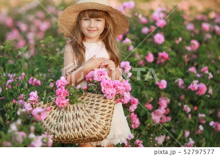 A little girl with beautiful long blond hair, dressed in a light dress and a wreath of real flowers 52797577