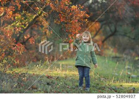 Funny kid girl pretending to be posing in autumn forest, wearing a green coat Funny kid girl pretending to be posing in autumn forest, wearing a green coat 52804937