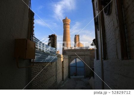 中央アジア　シルクロードの旅　ウズベキスタン　ブハラ　路地と夕陽に映えるカラーン・ミナレットとモスク 52829712