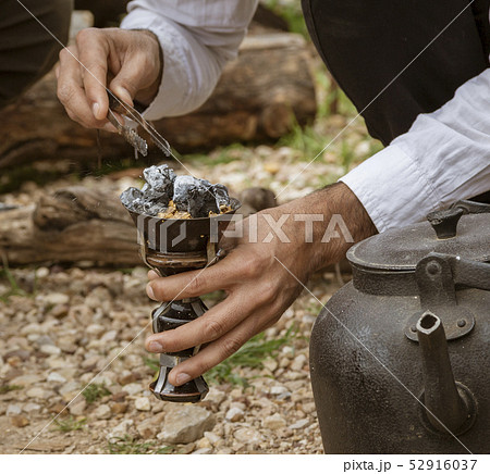 Man tends to hot coals for smoking water pipe 52916037
