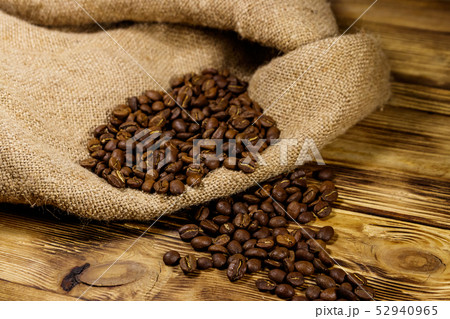 Roasted coffee beans on sackcloth on wooden table Roasted coffee beans on sackcloth on wooden table 52940965